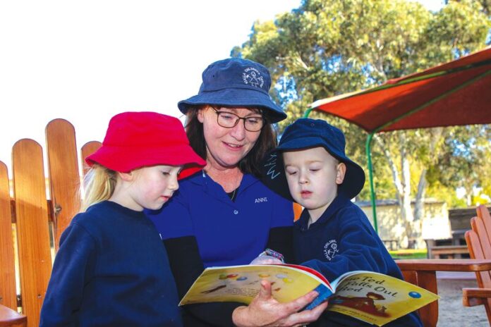 SO MUCH MORE THAN A JOB...kindergarten students Chelsea Ahmet and Max Wallace-Board enjoy a story with their teacher, Anni Russell at Kialla Childrens Centre.Photo: Natasha Fujimoto